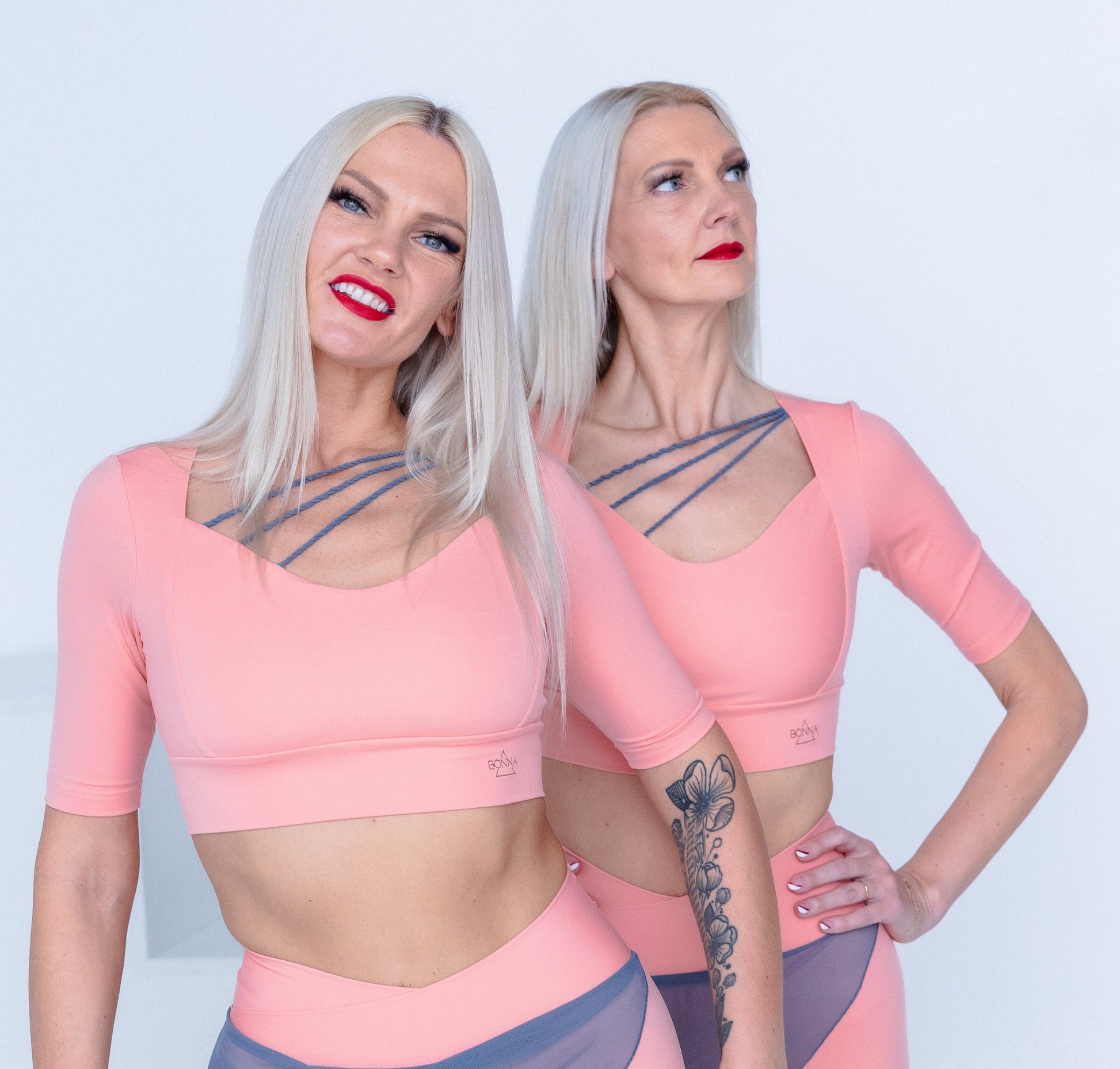 Two women wearing matching pink and gray athletic outfits on a white background