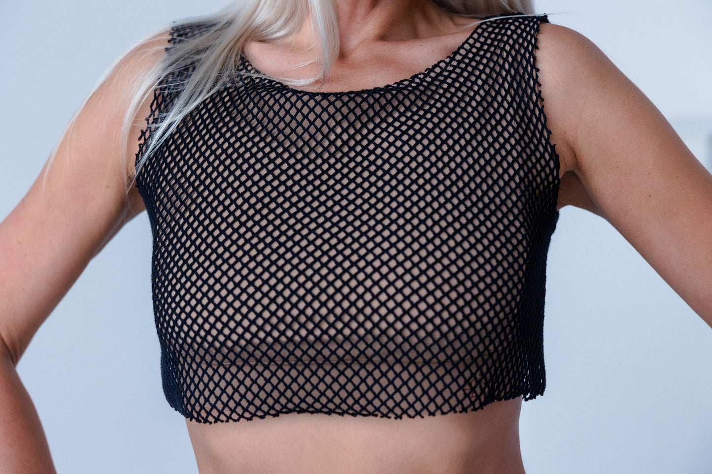 Black fishnet top worn by a person on a plain background