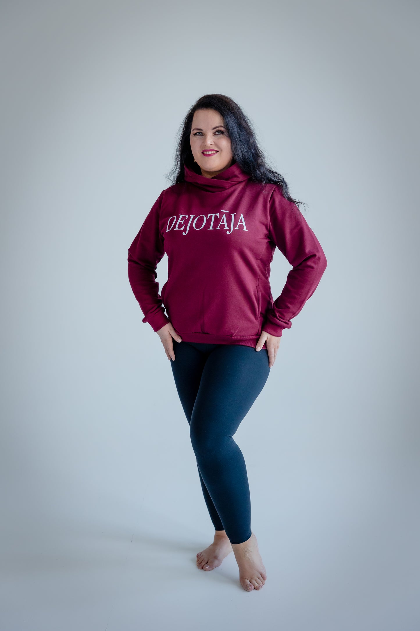 Woman wearing a burgundy hoodie with 'DEJOTAJA' text on a plain background