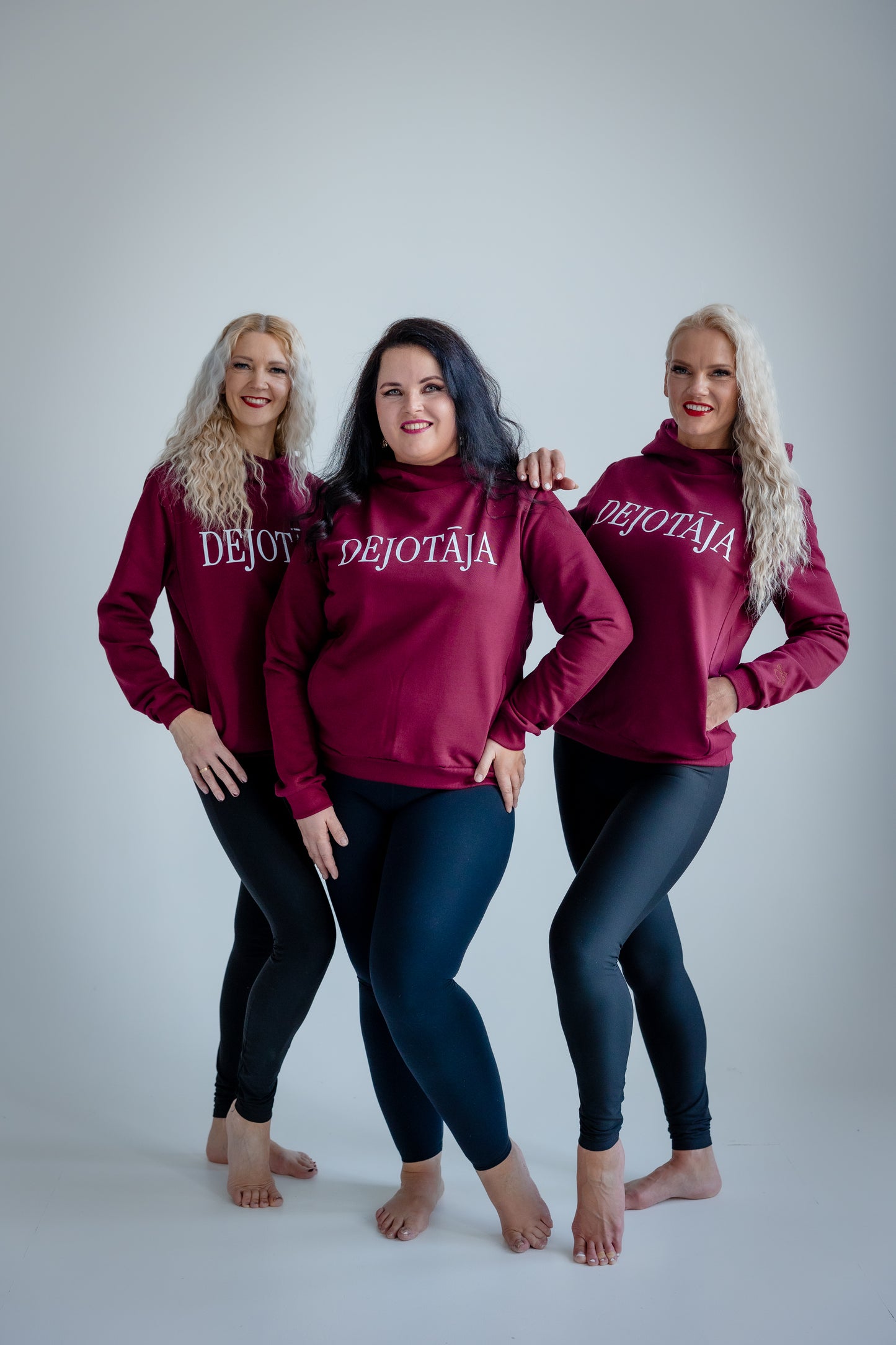 Three women wearing burgundy hoodies with 'DEJOTAJA' text on a white background
