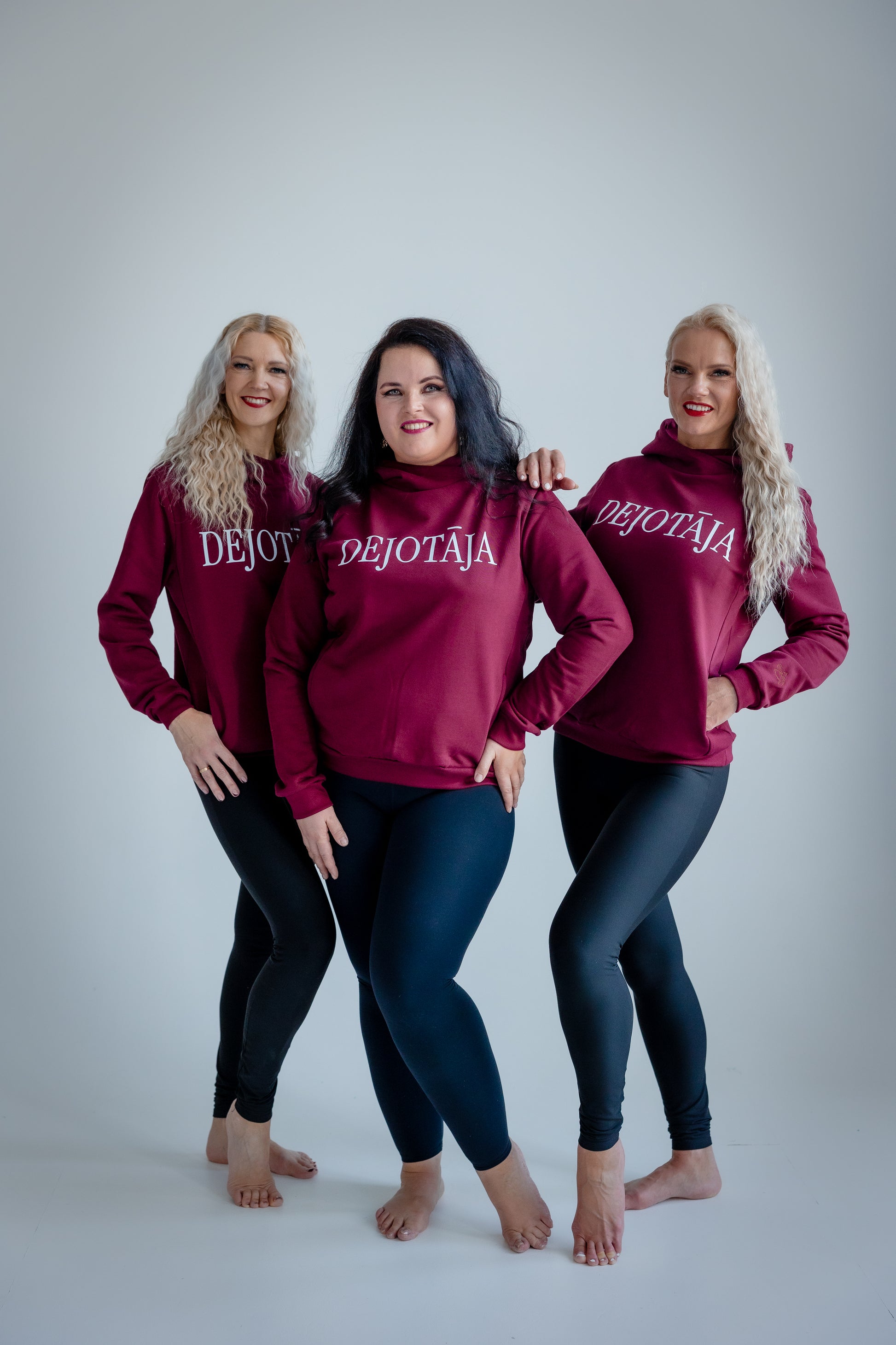 Three women wearing burgundy hoodies with 'DEJOTAJA' text on a white background