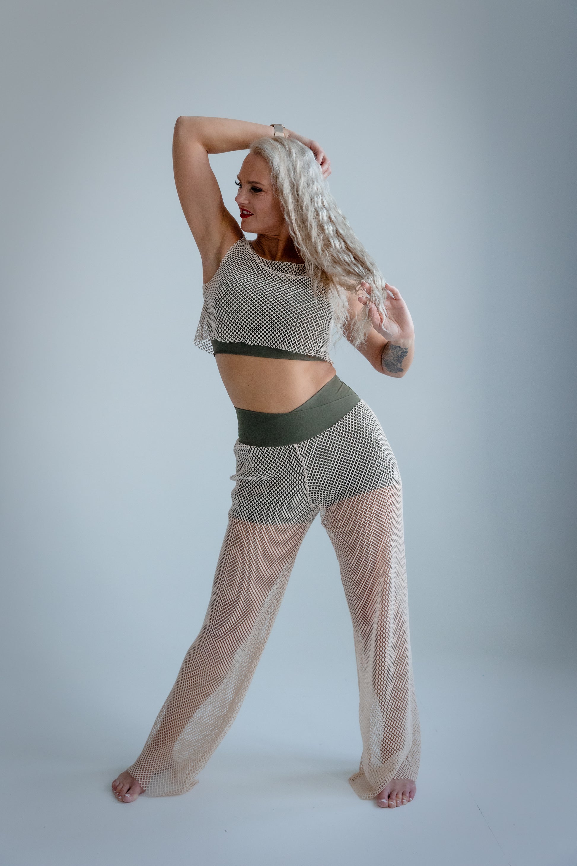 Woman wearing a mesh outfit on a plain background