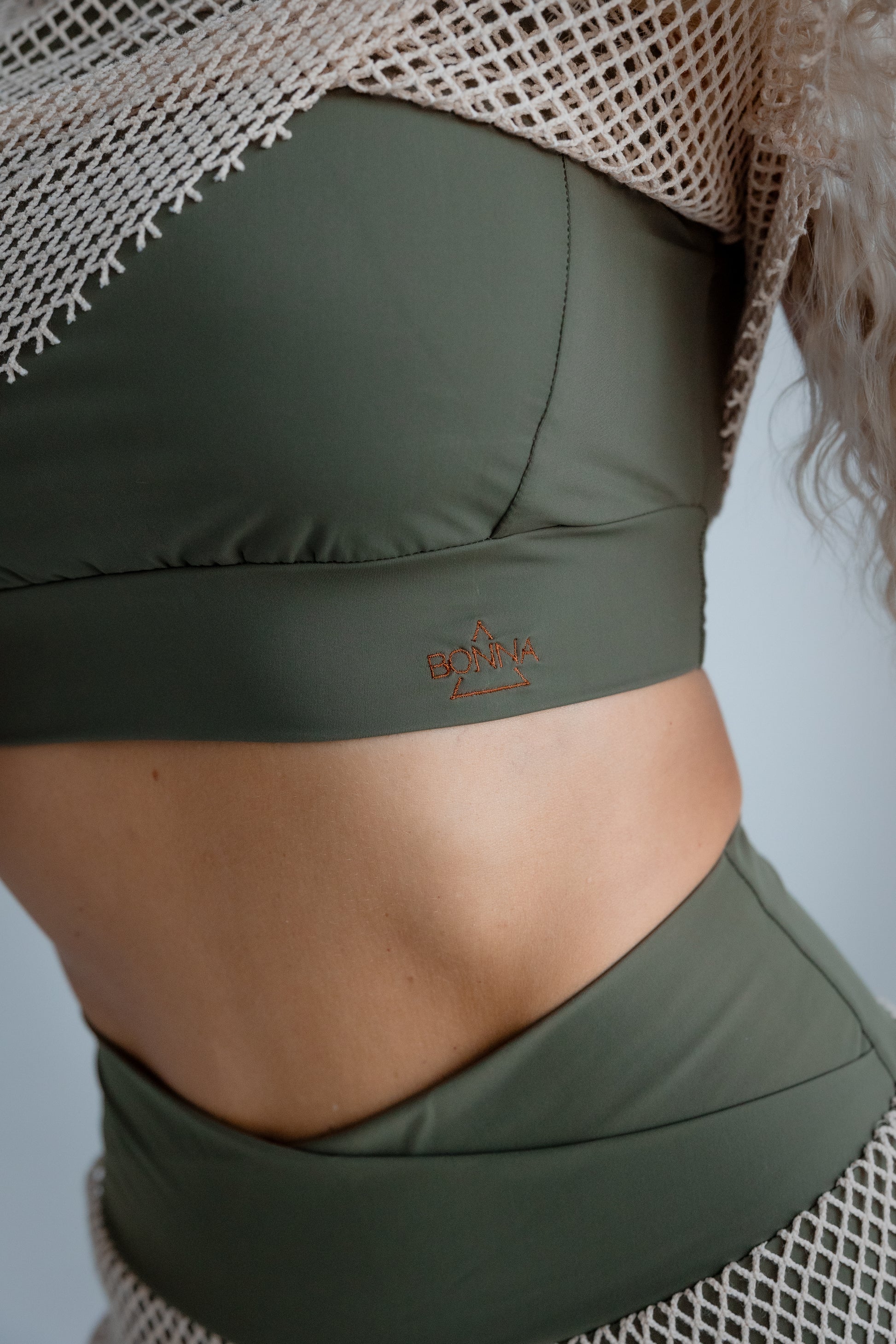 Green sports bra and shorts with a brand logo on a neutral background