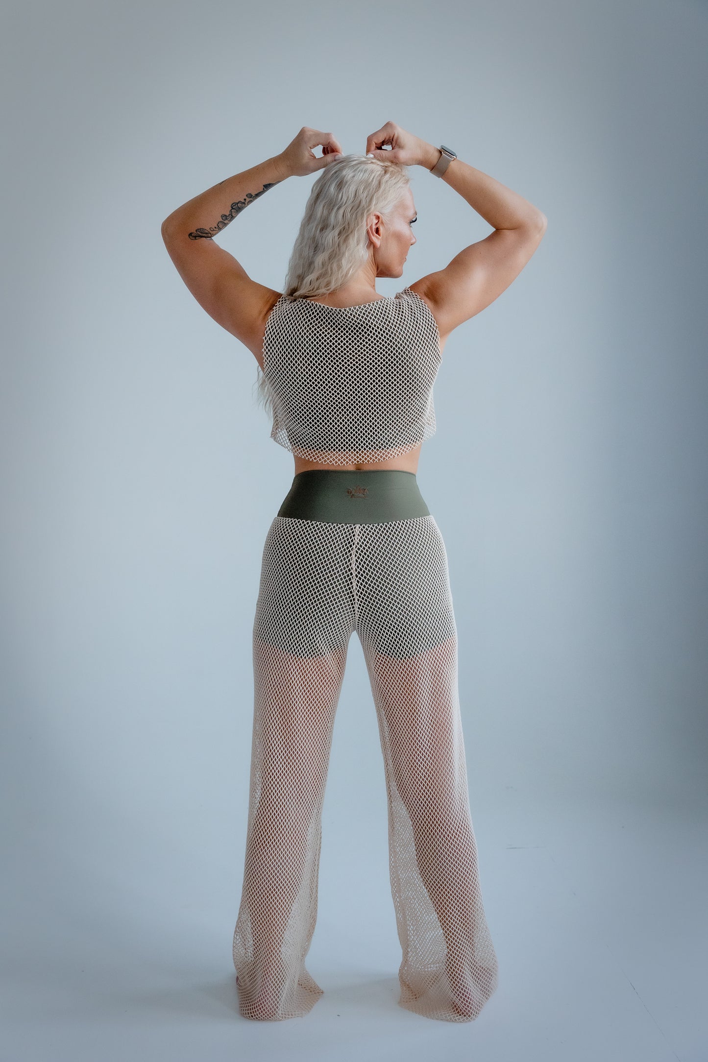 Person wearing a patterned top and sheer pants on a plain background