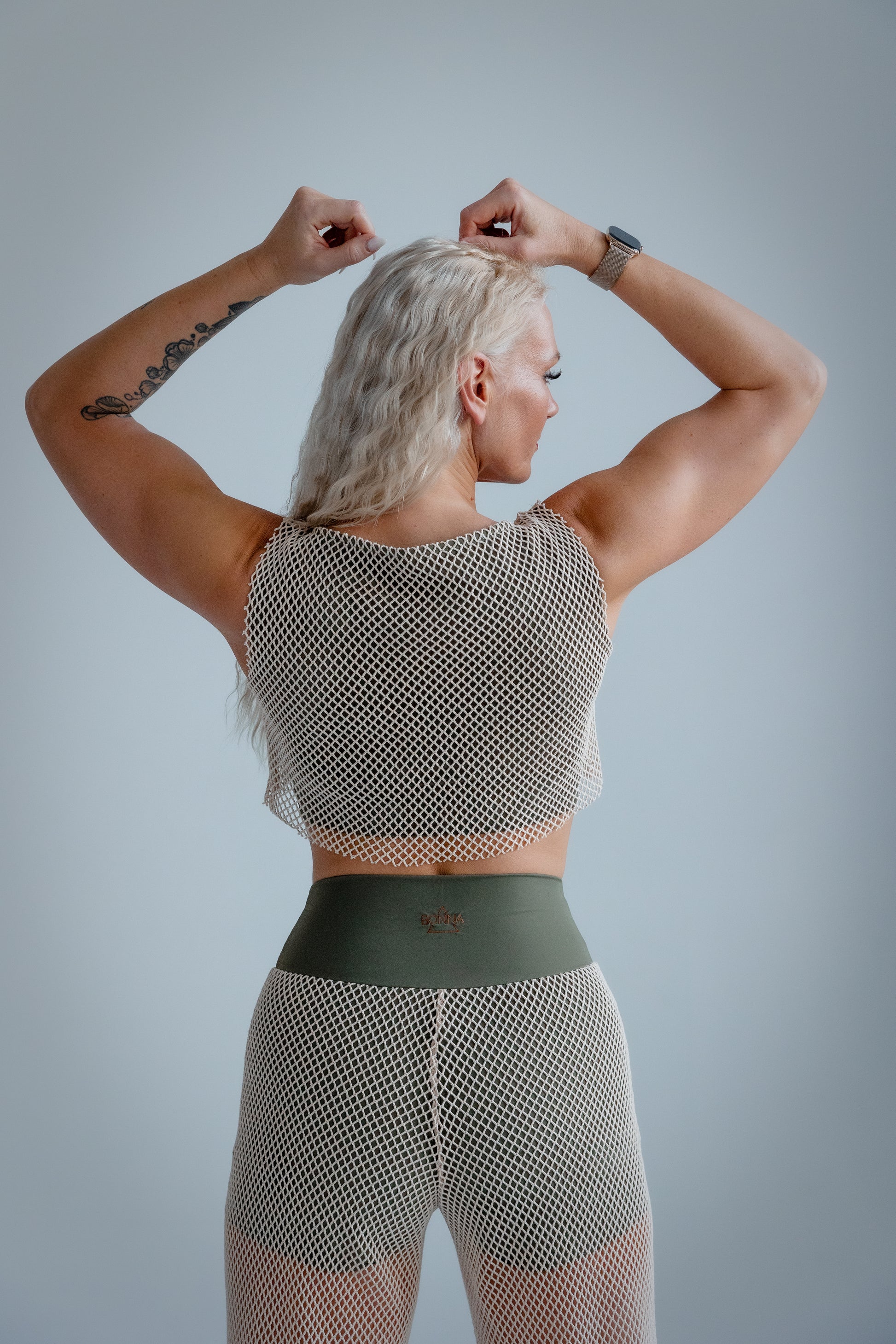 Person wearing a patterned top and leggings against a plain background