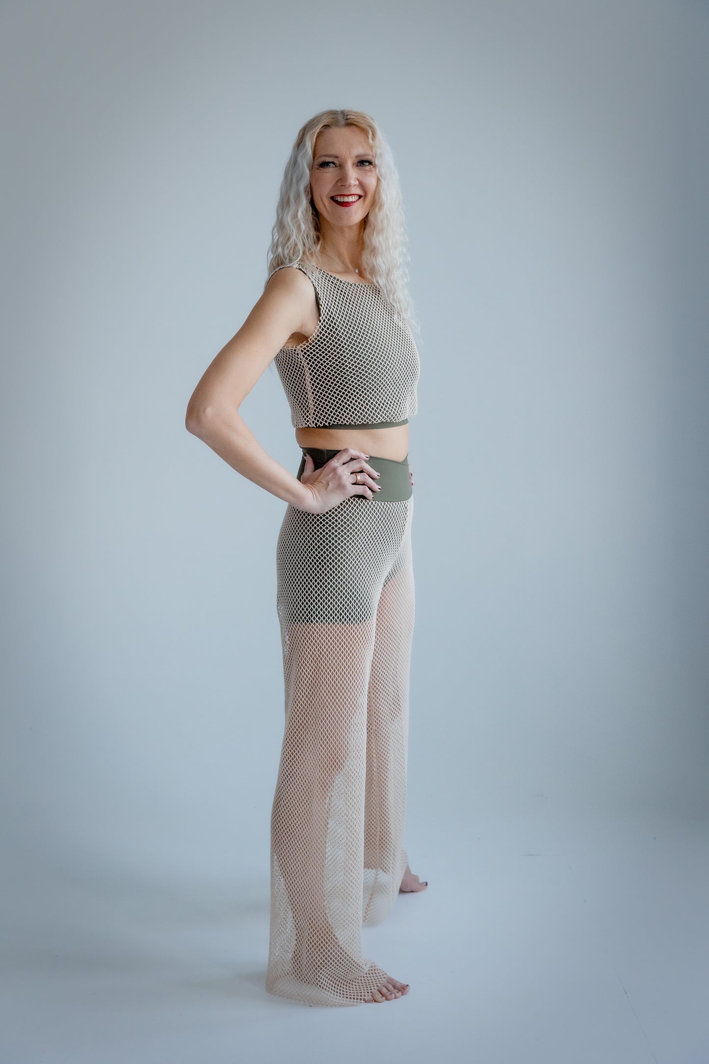 Woman wearing a patterned top and sheer pants on a plain background