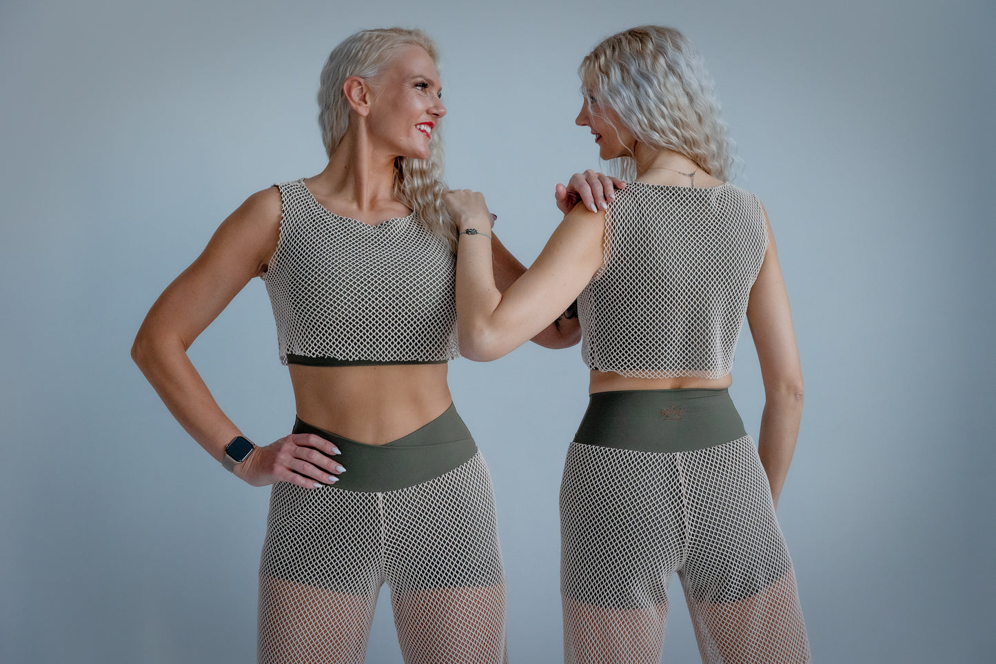 Woman wearing a mesh top and green shorts against a plain background