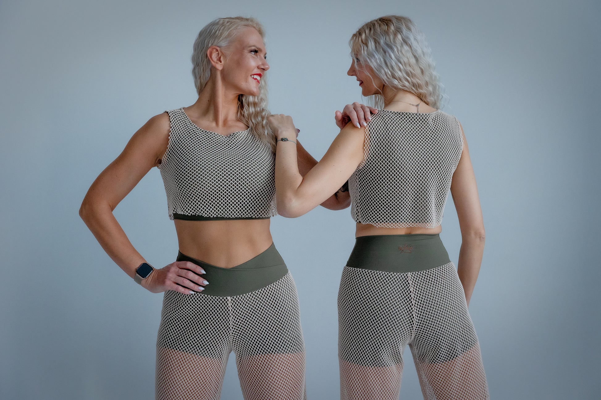 Woman wearing a mesh top and green shorts against a plain background